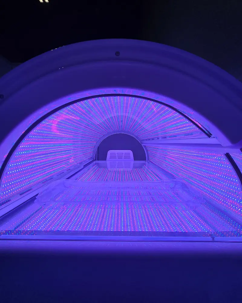 The bed from the foot end, lit, in a dim room